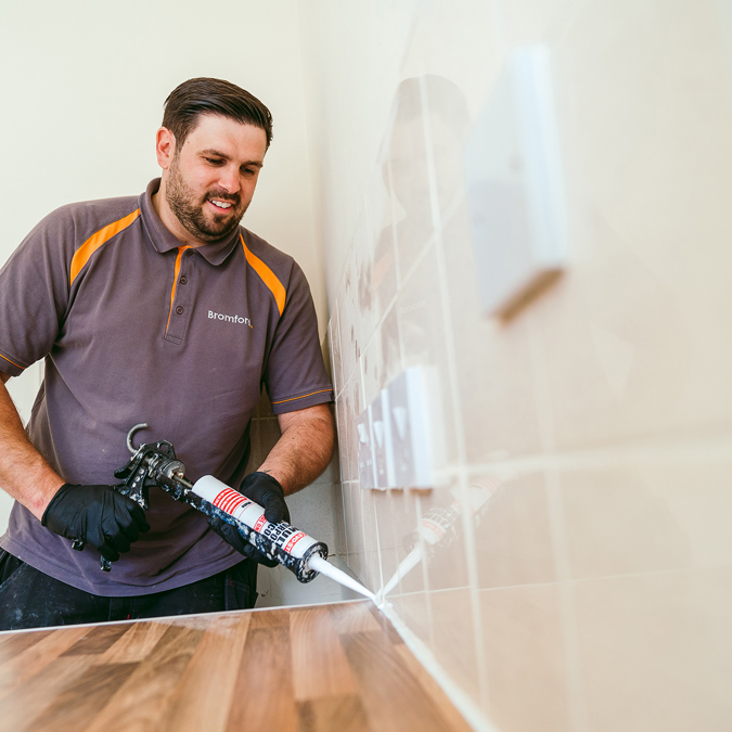 A Bromford colleague making a repair in a kitchen