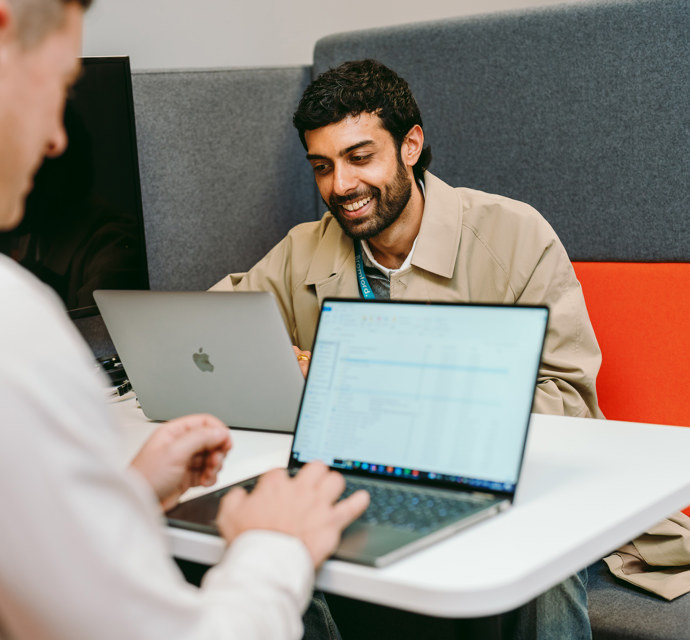 2 people on laptops smiling