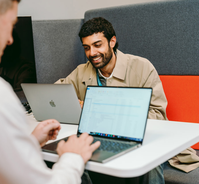 2 people on laptops smiling