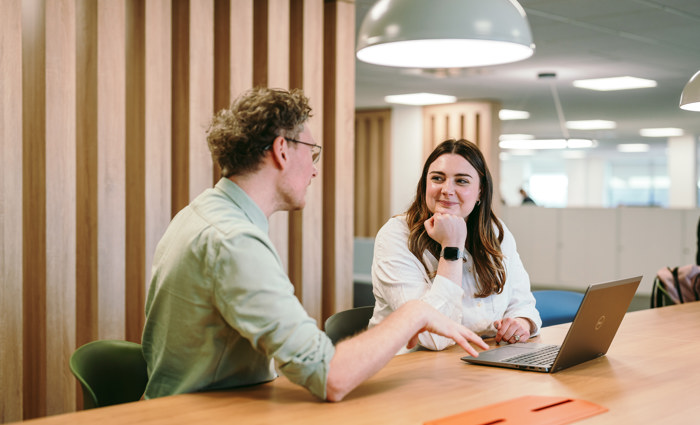 Two people sat at a desk talking