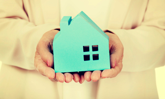 Small blue house being held in a persons hands