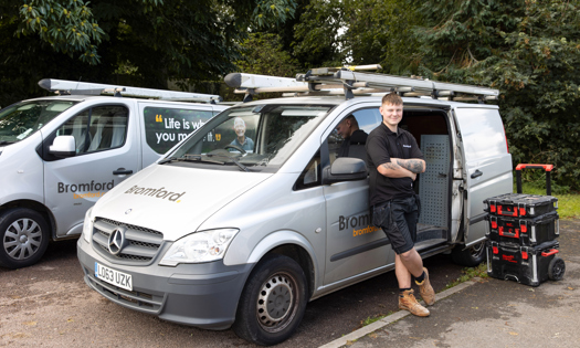 Bromford colleague smiling and standing in front of a Bromford van 