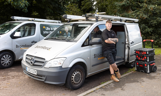 Bromford colleague smiling and standing in front of a Bromford van 