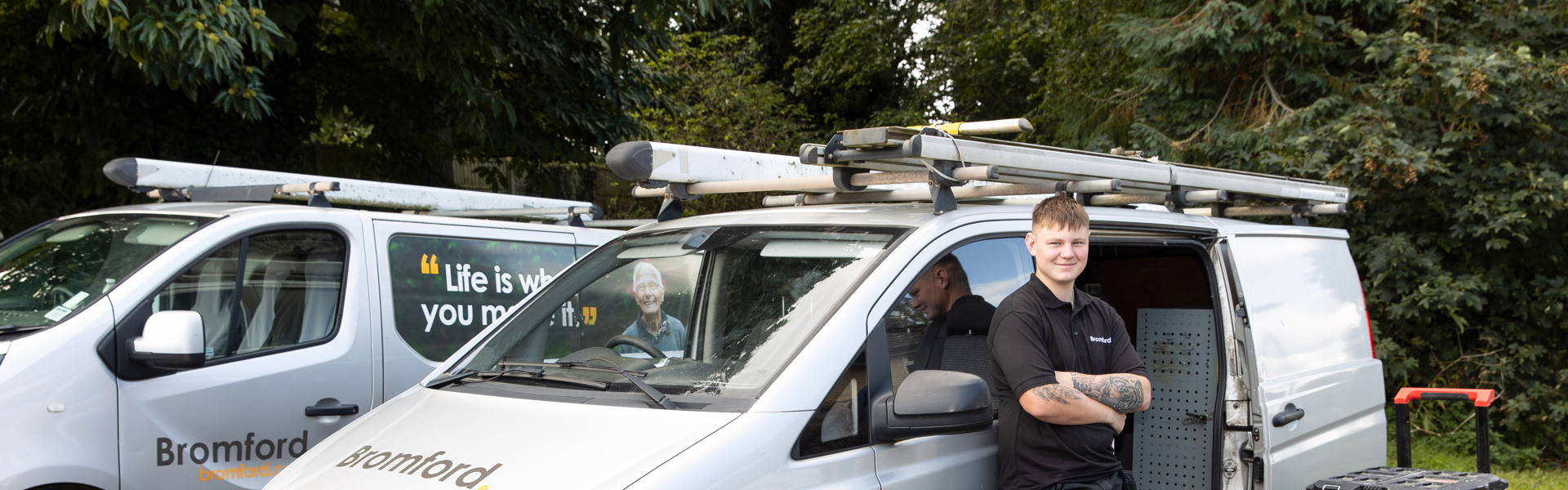 Bromford colleague smiling and standing in front of a Bromford van 