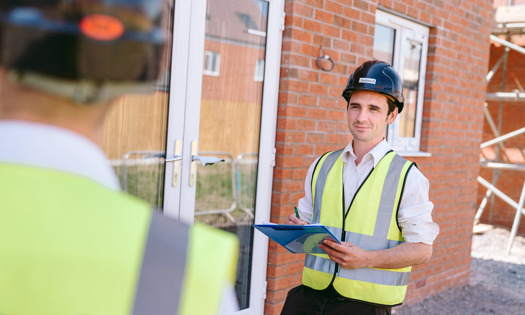 Person wearing a hard hat on holding a clipboard