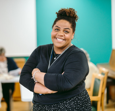 A woman stands with her arms crossed in an art room