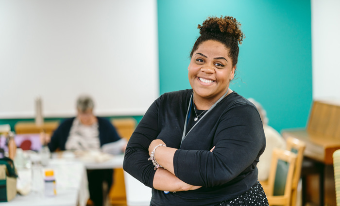 A woman stands with her arms crossed in an art room