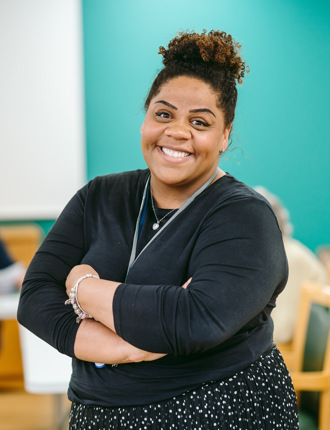 A woman stands with her arms crossed in an art room