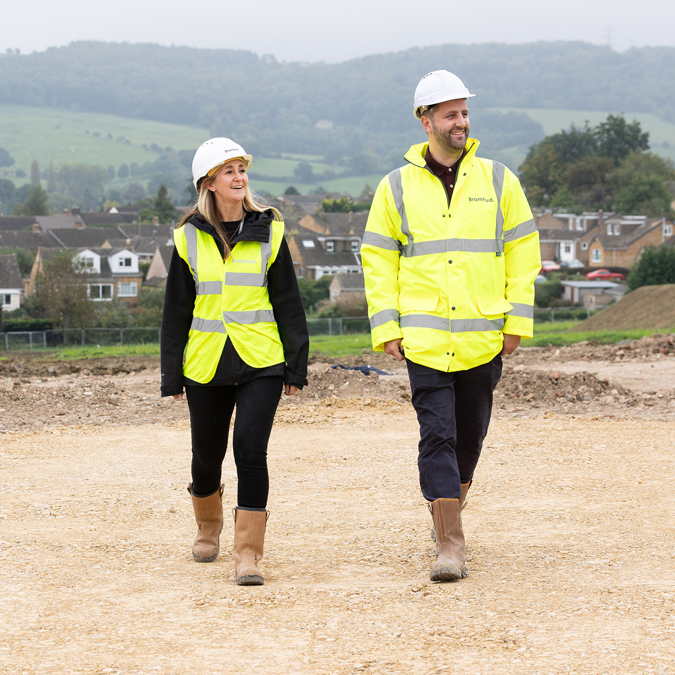 Two bromford colleagues wearing high visability coats, walking on a constructionsite