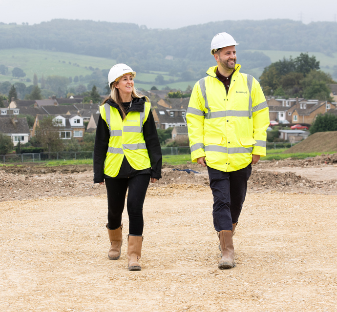 Two bromford colleagues wearing high visability coats, walking on a constructionsite