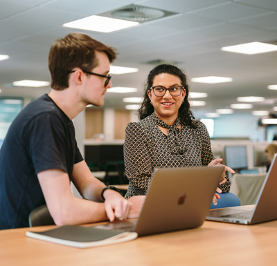 Two people sat at a desk talking