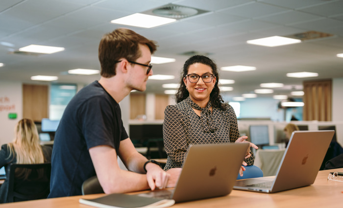 Two people sat at a desk talking