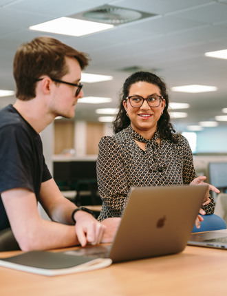 Two people sat at a desk talking