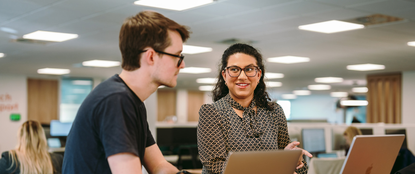 Two people sat at a desk talking