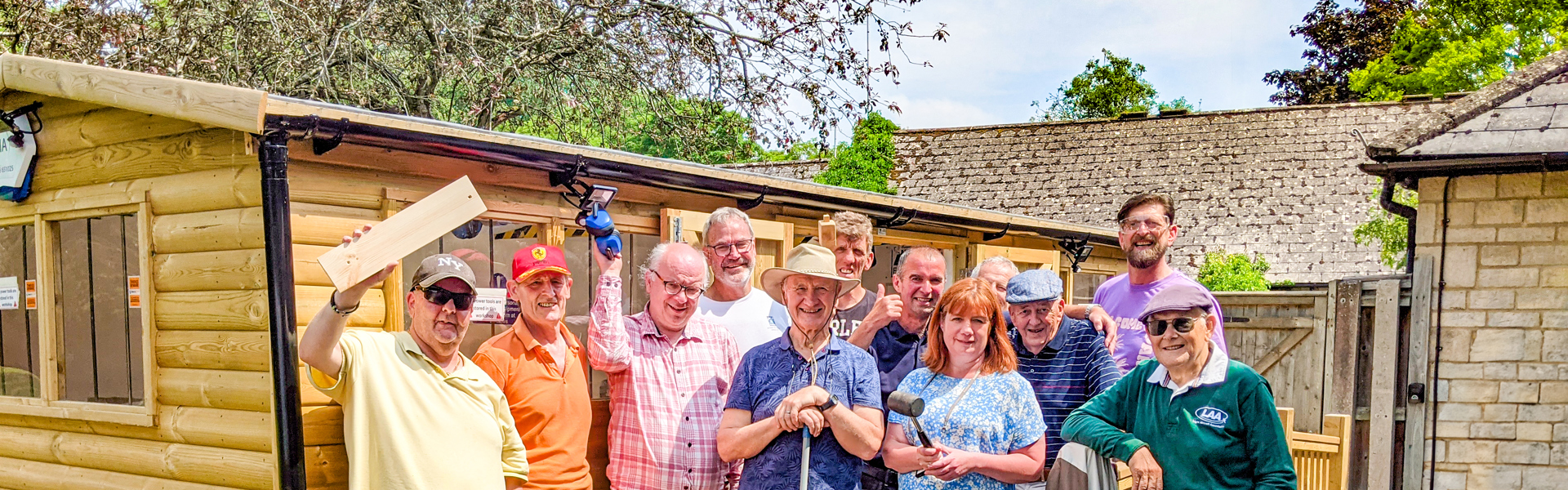 A group of 12 people stand in front of a shed