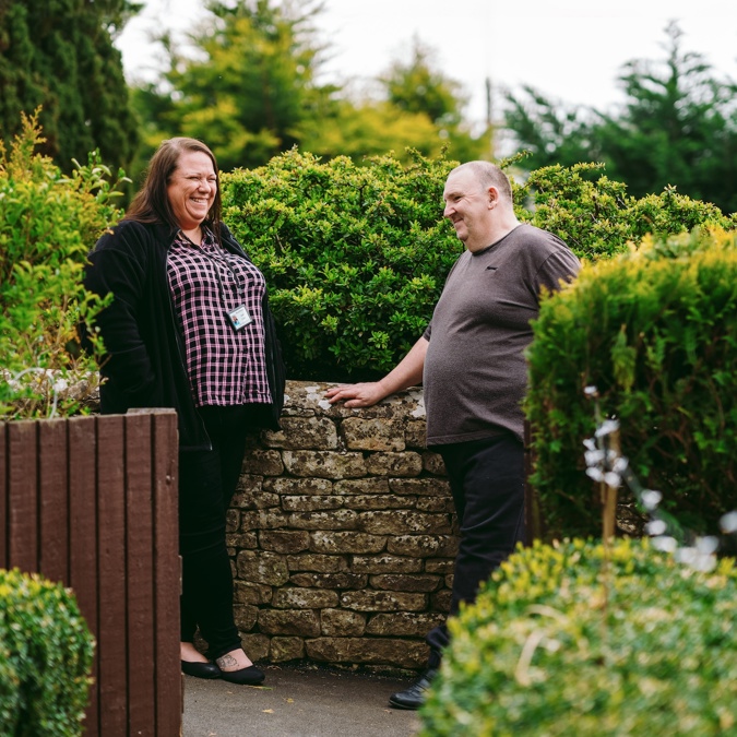 A Bromford neighbourhood coach talking to a male customer in his garden