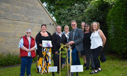 People standing in front of a rose which they planted 