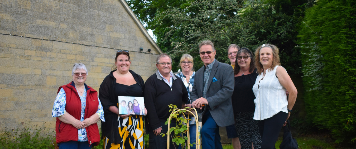 People standing in front of a rose which they planted 